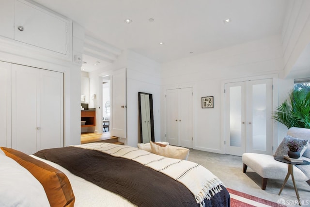 bedroom with multiple closets, french doors, and light carpet