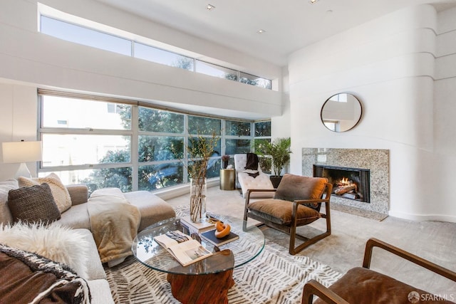 carpeted living area featuring a high end fireplace and a high ceiling