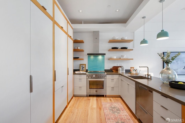 kitchen with a sink, appliances with stainless steel finishes, wall chimney exhaust hood, light wood-type flooring, and open shelves