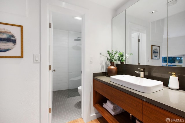 bathroom featuring tiled shower, vanity, and toilet