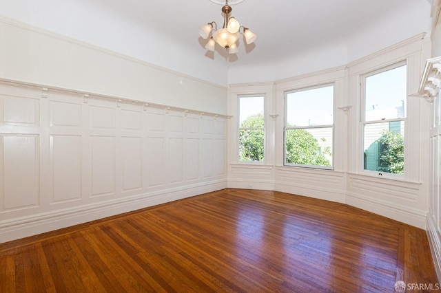 empty room with a notable chandelier and dark wood-type flooring