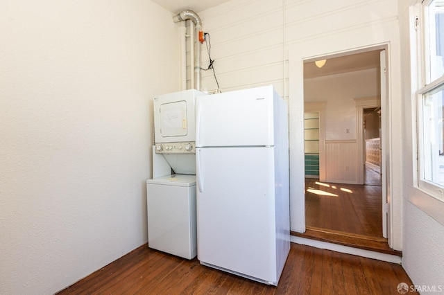 laundry room with dark hardwood / wood-style flooring and stacked washer / dryer