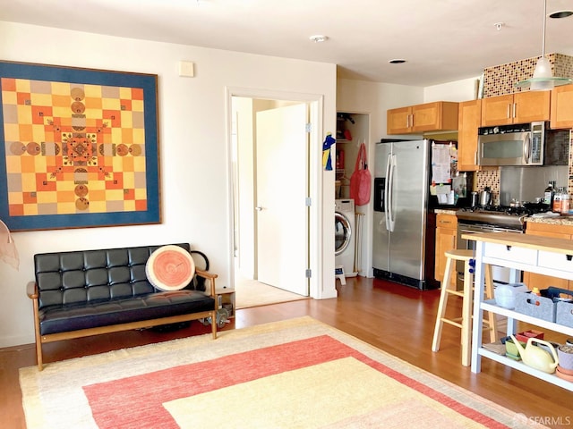 81 Frank Norris St Unit 501, San Francisco, CA 94109 - kitchen featuring appliances with stainless steel finishes, wood finished floors, washer / clothes dryer, backsplash, and decorative light fixtures