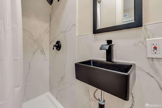 full bathroom with a sink, visible vents, tile walls, and a stall shower