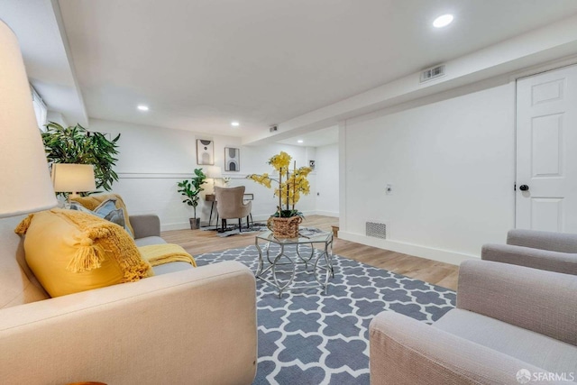 living room with recessed lighting, visible vents, and wood finished floors