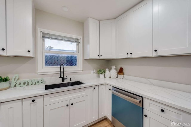 kitchen with dishwasher, white cabinets, light stone countertops, and a sink