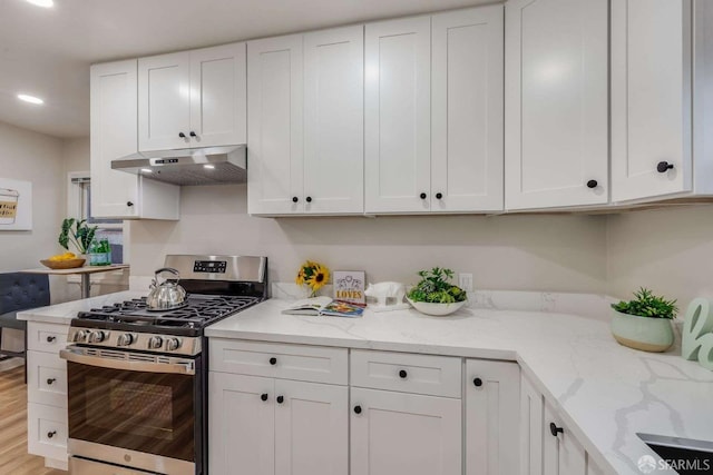 kitchen with gas range, white cabinets, and under cabinet range hood