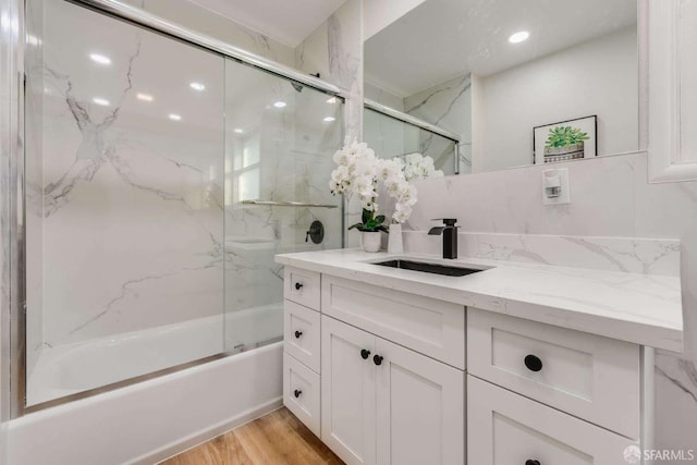 bathroom with vanity, wood finished floors, and enclosed tub / shower combo