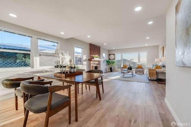 dining room featuring recessed lighting, light wood-style floors, and a brick fireplace