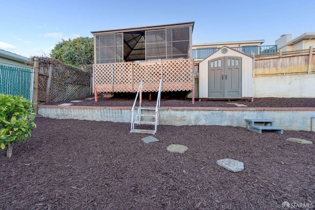 view of front facade with fence, a storage shed, an outdoor structure, and a sunroom