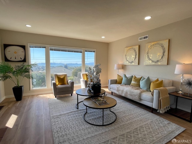 living area with recessed lighting, wood finished floors, visible vents, and baseboards