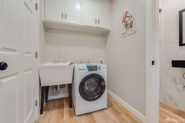 washroom featuring light wood finished floors, cabinet space, washer / clothes dryer, and baseboards