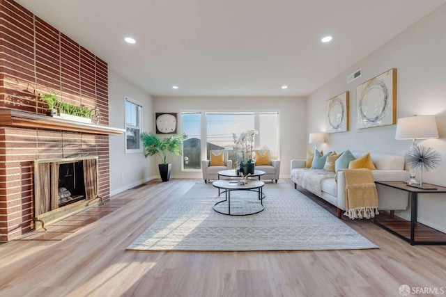 living area featuring wood finished floors, visible vents, baseboards, a fireplace, and recessed lighting