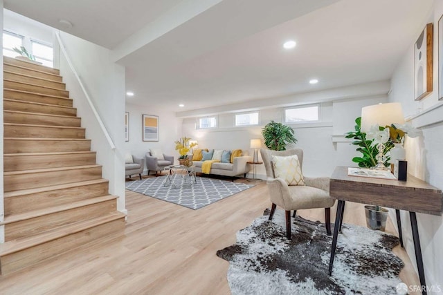 living room featuring light wood finished floors, recessed lighting, and stairs