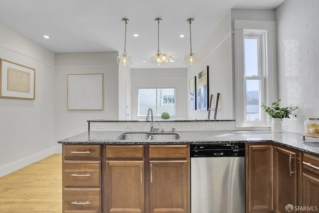 kitchen with dishwasher, light hardwood / wood-style flooring, sink, and stone countertops