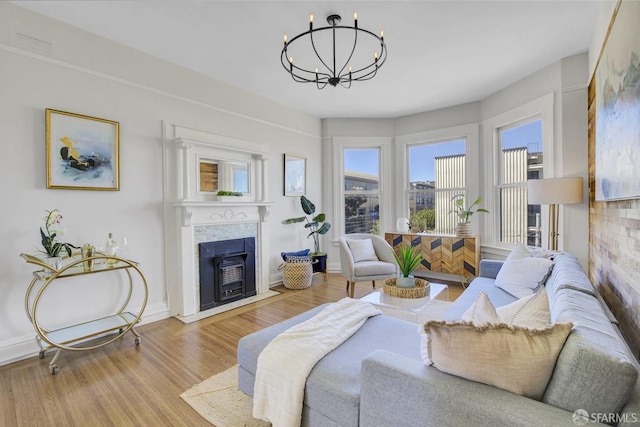 living room with light hardwood / wood-style flooring, an inviting chandelier, and a fireplace