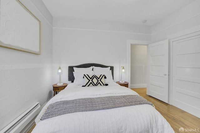 bedroom featuring light hardwood / wood-style floors and a baseboard heating unit