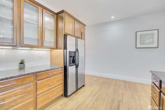 kitchen with light hardwood / wood-style flooring, backsplash, stainless steel fridge with ice dispenser, and stone countertops