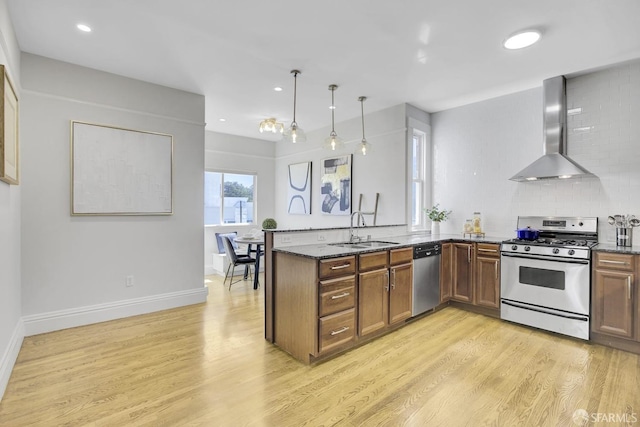 kitchen with gas stove, dishwasher, sink, wall chimney exhaust hood, and light hardwood / wood-style flooring