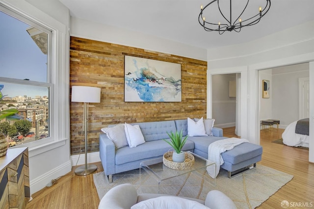 living room with an inviting chandelier, light wood-type flooring, and wood walls