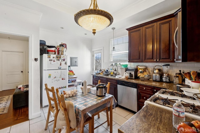 kitchen with tasteful backsplash, freestanding refrigerator, pendant lighting, dishwasher, and a sink