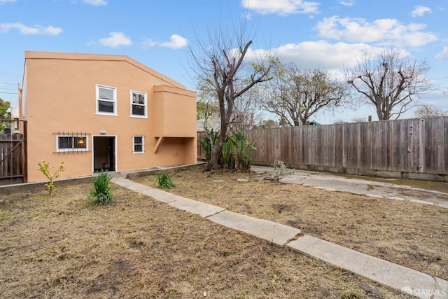 view of home's exterior with fence, a lawn, and stucco siding