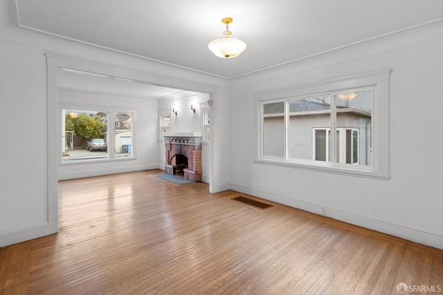 unfurnished living room featuring light wood-type flooring, baseboards, a fireplace, and visible vents