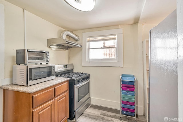3233 Ellis St, Berkeley, CA 94703 - kitchen featuring stainless steel appliances, under cabinet range hood, light wood-style floors, light countertops, and brown cabinets
