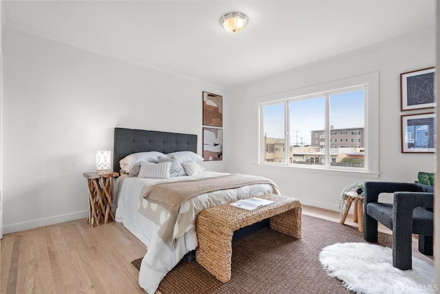 bedroom with light wood finished floors, baseboards, and ornamental molding