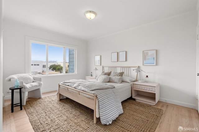 bedroom featuring light wood finished floors and baseboards