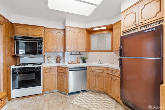 kitchen with black microwave, stainless steel dishwasher, freestanding refrigerator, decorative backsplash, and gas range