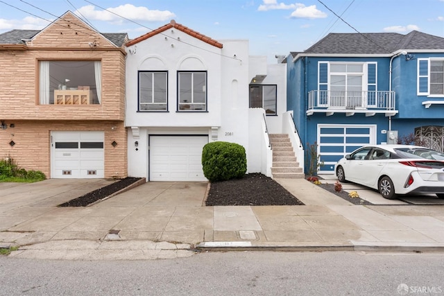 multi unit property with stairs, concrete driveway, a garage, and stucco siding