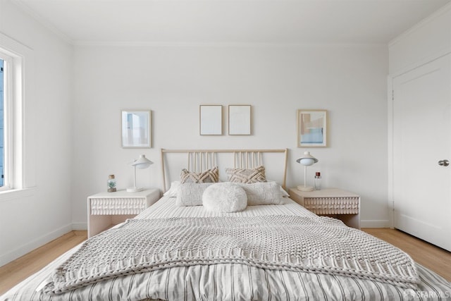 bedroom featuring ornamental molding, light wood-type flooring, multiple windows, and baseboards