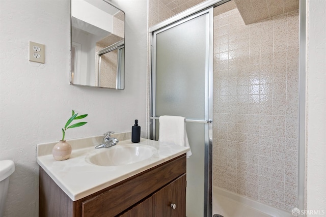 bathroom featuring toilet, a shower stall, and vanity