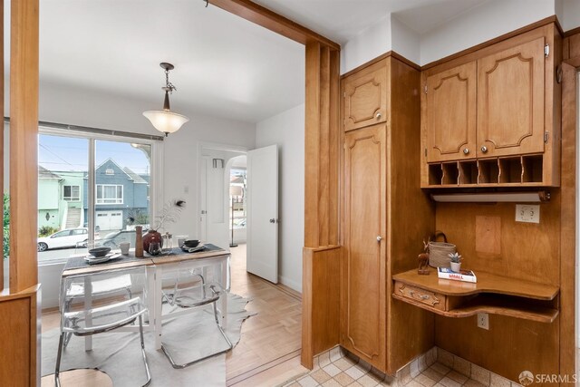 kitchen featuring arched walkways, hanging light fixtures, and brown cabinets