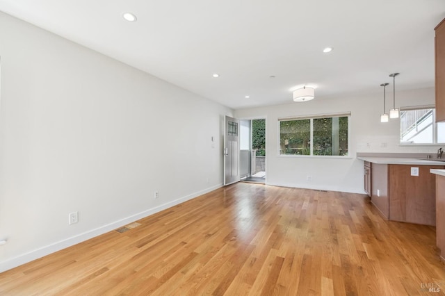 unfurnished living room with light hardwood / wood-style floors and sink