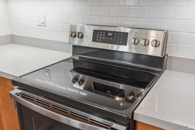 room details with stainless steel electric stove and decorative backsplash