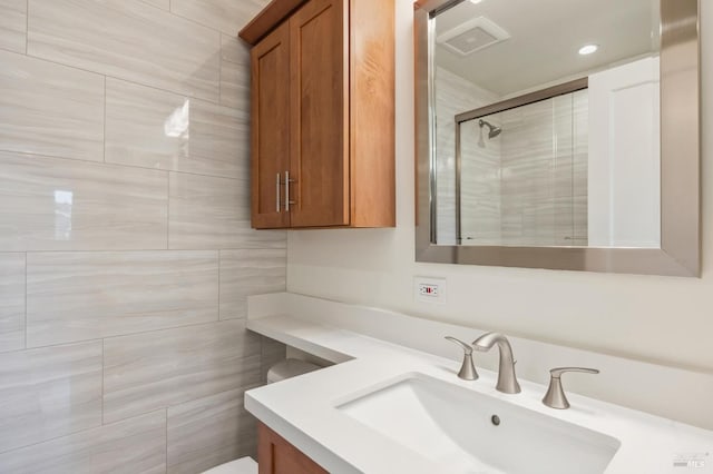 bathroom featuring a shower with door and vanity