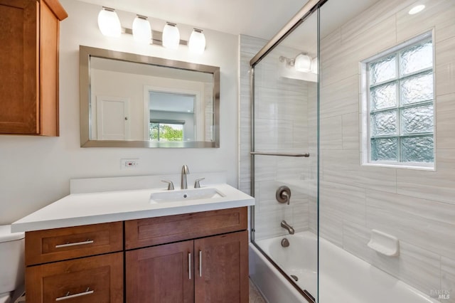 full bathroom with vanity, a healthy amount of sunlight, and bath / shower combo with glass door