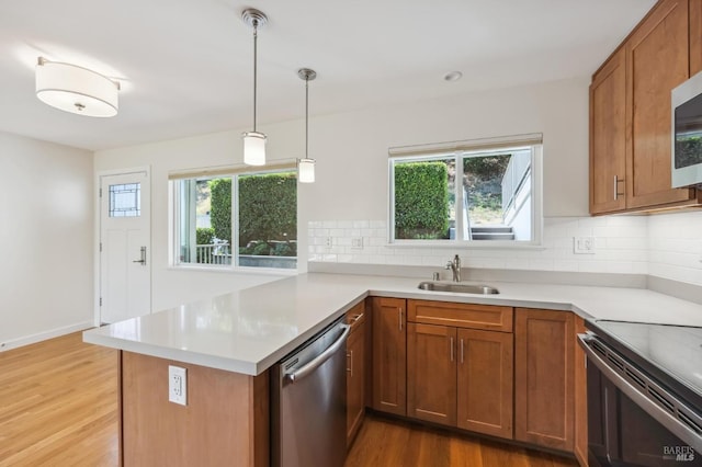 kitchen featuring kitchen peninsula, tasteful backsplash, stainless steel dishwasher, sink, and wood-type flooring