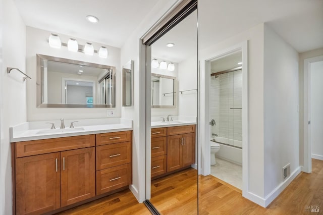 full bathroom with vanity, hardwood / wood-style flooring, toilet, and bath / shower combo with glass door