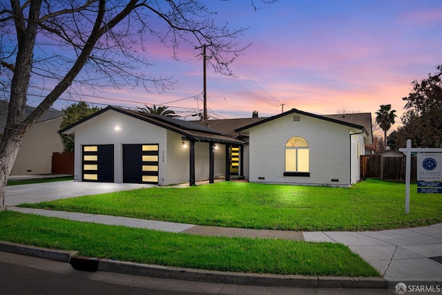 view of front of house with driveway, a lawn, crawl space, an attached garage, and stucco siding