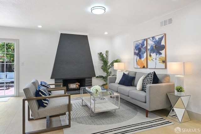 living room with visible vents, ornamental molding, wood finished floors, a fireplace, and recessed lighting