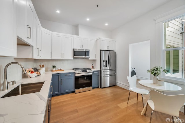 289 Church St, San Francisco, CA 94114 - kitchen featuring appliances with stainless steel finishes, white cabinetry, light wood finished floors, tasteful backsplash, and light stone countertops