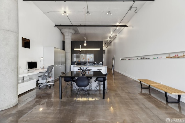 dining space featuring concrete floors and a towering ceiling