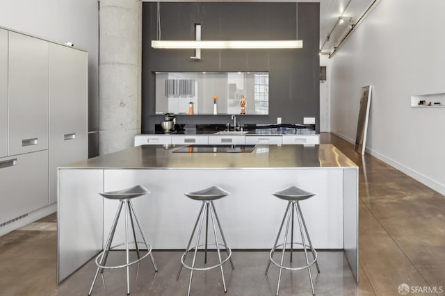 kitchen featuring concrete flooring, a center island, a breakfast bar, and a towering ceiling