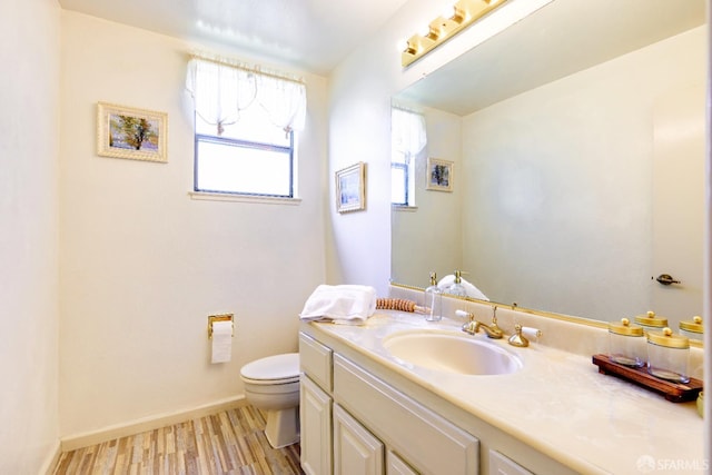 bathroom featuring toilet, wood finished floors, vanity, and baseboards