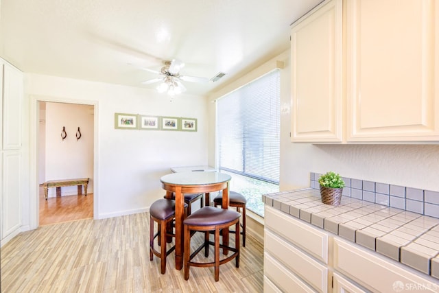 dining room with light wood finished floors, ceiling fan, and baseboards