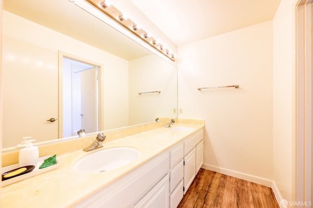 bathroom with wood finished floors, double vanity, and baseboards