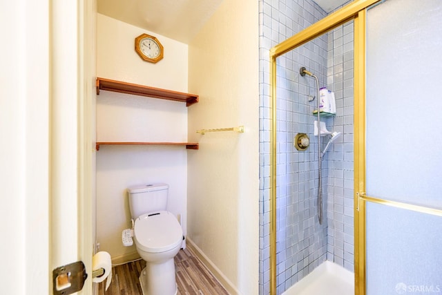 bathroom with a shower stall, wood finished floors, toilet, and baseboards